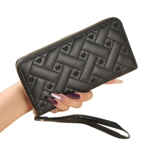 Black quilted long wallet with heart embroidery and gold zipper wristlet held by hand