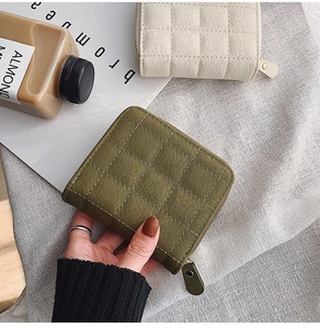 Detail of quilted leather mini wallets in army green and cream with zipper closure