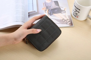 Close-up of a charcoal grey quilted square coin purse with premium zipper and leather puller