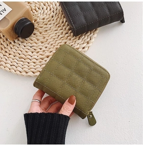 Close-up of olive green and black quilted mini wallets with a smooth zipper closure