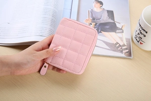Close-up of pink quilted faux leather mini wallet with gold zipper detail held by hand