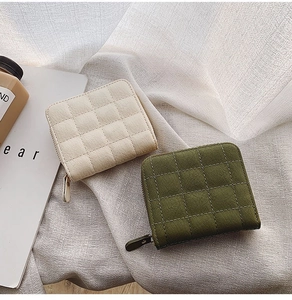 Detail of mini quilted zipper wallets in cream and olive green with neat stitching