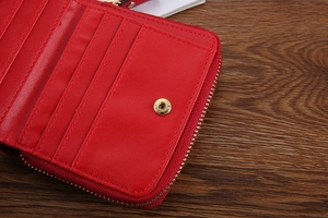 Detail view of red leather wallet interior featuring multiple card slots and gold hardware