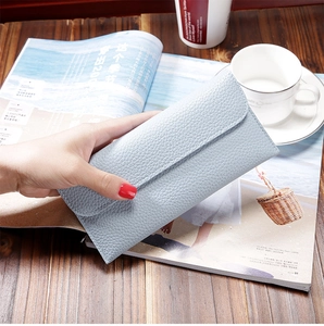 Detail of light blue lychee grain leather long wallet held in a lifestyle setting