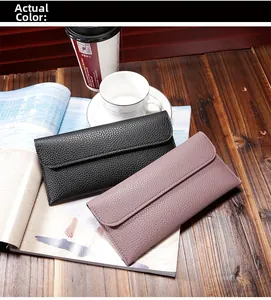 Detailed view of black and pink pebble-grain long envelope wallets on wooden desk