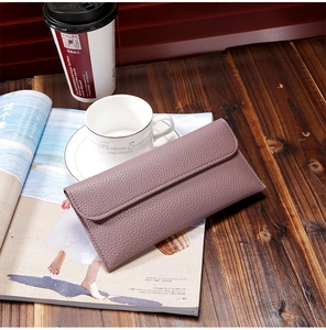 Chic mauve long leather wallet with lychee pattern on a dark wooden table background