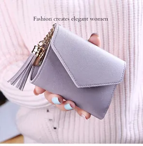 Detail of lilac trifold wallet with pebble leather texture and gold tassel charm