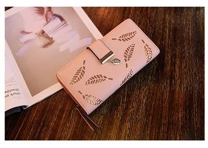 Détail d'un portefeuille rose avec motif feuilles découpées et pendentif feuille