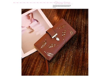 Détail d'un long portefeuille en cuir marron avec feuilles évidées et pendentif en métal