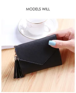 Close-up of black lychee grain trifold wallet with tassel charm held in hand