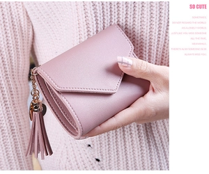 Detailed view of pink pebble grain leather wallet with fringe pendant and metal chain