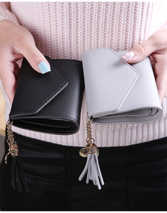 Detail of short leather wallets for women with tassels and gold chains held by model