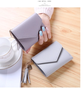 Detail of slim tri-fold wallets in purple and grey with tassel and heart pendant