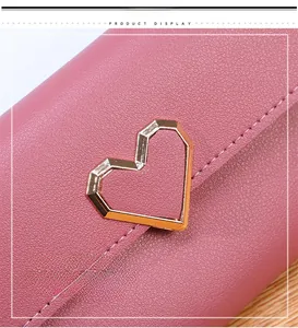 Gros plan d'un portefeuille rose en cuir grainé avec un fermoir en métal doré en cœur