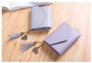 Detail view of tri-fold wallets with litchi texture, heart pendants, and tassels