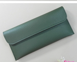 Detail view of a dark green long wallet featuring pebbled leather texture and flap closure