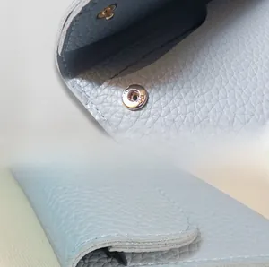 Detail of light blue lychee pattern leather wallet featuring a durable metal snap closure