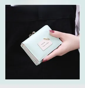 Close-up of mint green tri-fold wallet with pearl accent and stylish metal snap closure
