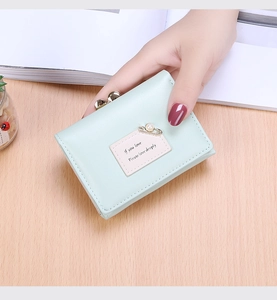 Detail of mint green tri-fold wallet featuring pearl pin and metal snap coin pocket