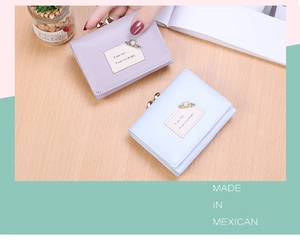 Close-up of pastel trifold wallets with metal clasps and pearl pin decoration