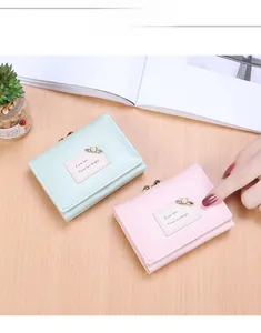 Close-up of minimalist trifold wallets in pink and mint green with pearl pins