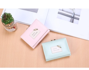 Detail of pink and mint green tri-fold wallets with vintage gold kiss-lock and pearl pin