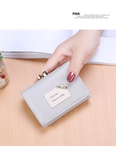 Close-up of light grey short wallet with gold pearl pin and vintage metal bead clasp
