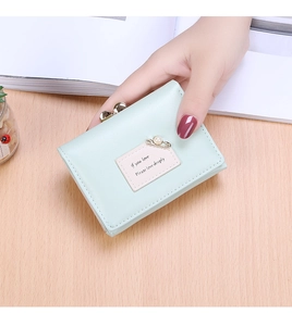 Close-up of mint green bi-fold wallet with pink patch and vintage gold metal clasp