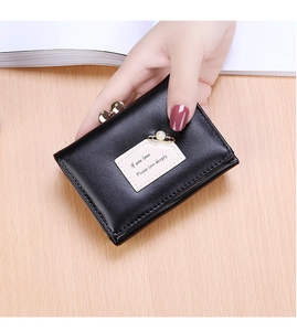 Detail of black leather tri-fold wallet with kiss-lock clasp and pearl pin decoration