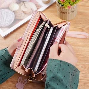 Pink long patchwork wallet with zipper, wristlet, and tassel charm on wooden table