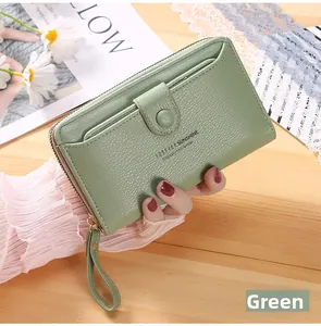 Detail of light green litchi texture wristlet wallet with a front snap pocket on wood surface