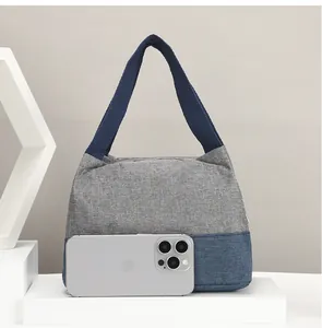 Detailansicht der zweifarbigen Segeltuchtasche im Größenvergleich mit einem Handy