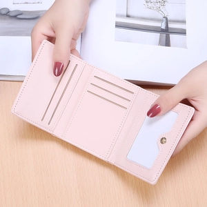 Pale pink tri-fold faux leather wallet featuring multiple card slots and clear ID window