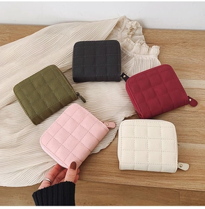 Quilted mini wallets with zipper in five colors displayed on white fabric and wood