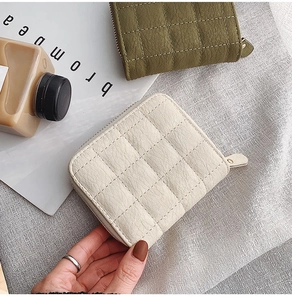 Detail of mini quilted PU leather coin purses in beige and green with metallic zippers