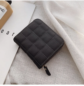 Detailed close-up of a quilted black mini zip wallet with elegant gold metal hardware