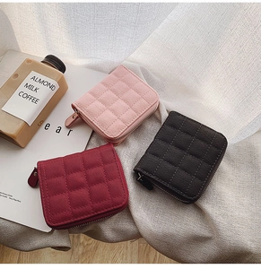 Detailed view of quilted mini wallets in pink, burgundy, and black with metal zippers