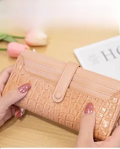 Detail showing stone textured apricot long wallet with multiple card slots and snap strap