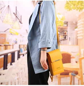 Petit sac de téléphone vertical jaune en cuir PU porté dans un décor de café élégant