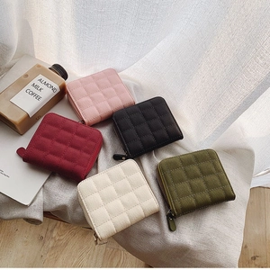 Mini quilted zipper wallets for women in five assorted colors on a soft white background