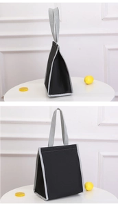 Detailed view of insulated canvas lunch bag with reinforced grey handles on white table