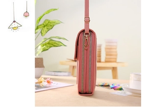 Détail du sac à bandoulière rose montrant la double fermeture éclair et métal doré