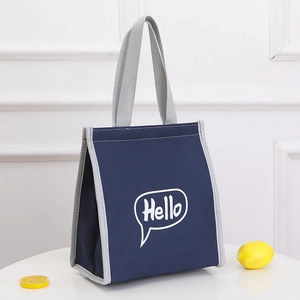Navy blue insulated lunch bag with grey trim and Hello print on a white table