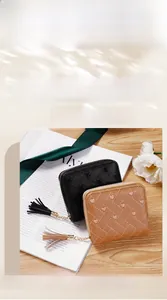 Détail de mini-portefeuilles brodés avec motifs de cœur et pompon sur support en bois