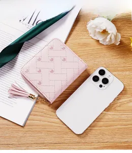 Petit portefeuille rose avec broderie cœur à côté d'un iPhone 14 pour l'échelle