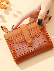 Detailed view of brown crocodile texture card holder with snap closure and gold zipper