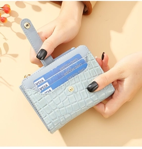 Close-up of light blue crocodile texture card holder with side zipper and snap closure