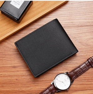 Detailed view of a black grainy leather bifold wallet on a rustic wooden background