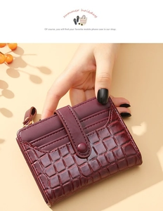 Macro detail of wine red crocodile embossed leather and smooth texture on short wallet
