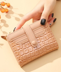 Close-up of beige crocodile pattern wallet with card slots and snap closure detail